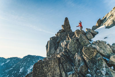 Man standing on rock by mountain against sky