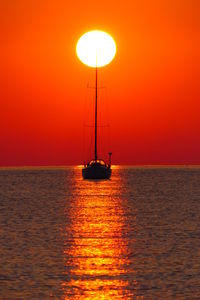 Sailboat sailing on sea against sky during sunrise