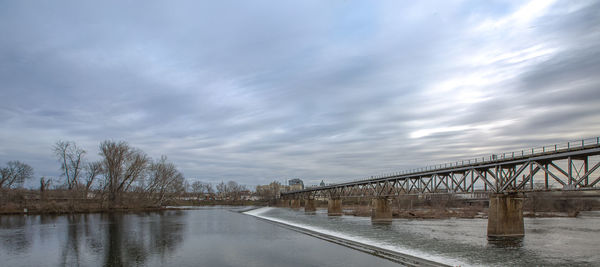 Bridge over river against sky during winter