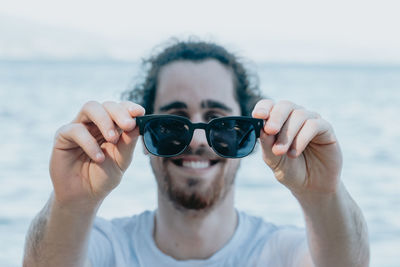 Portrait of young man wearing sunglasses against sky