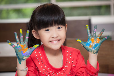 Portrait of smiling girl with painted messy hands