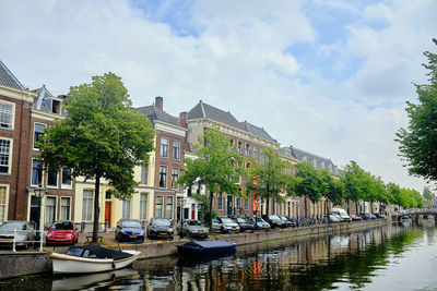 Boats moored in canal by buildings against sky