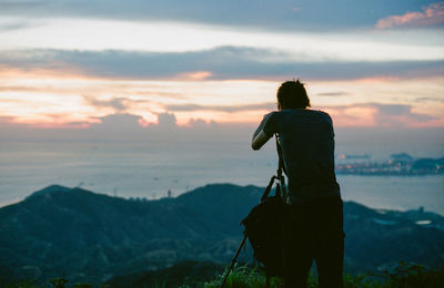 Rear view of man looking at sea against sky