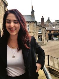 Portrait of smiling young woman standing against building