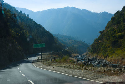 Road amidst trees against mountains