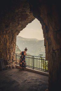 Girl standing on railing by mountain