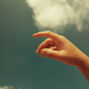 Cropped hand of person gesturing against sky