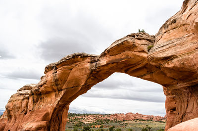 Low angle view of rock formation against cloudy sky