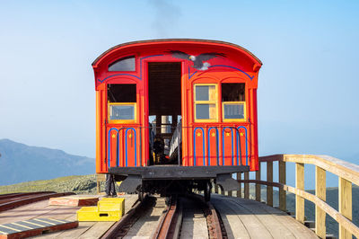 Red train on railroad track against sky