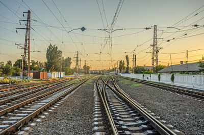 An old electric train drives up to the station platform along the rails at sunset