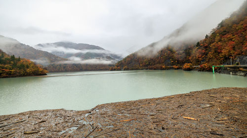 Brown wood block floating in front of the dam and river mountain fog view background in autumn 