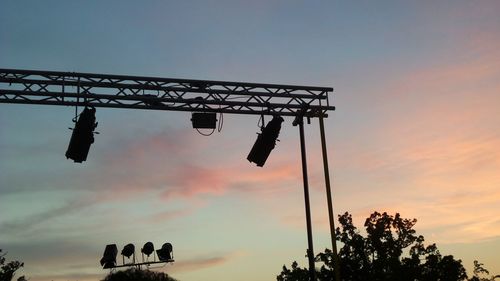 Low angle view of silhouette cranes against sky at sunset