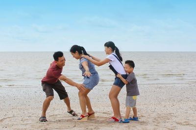 Happy family enjoying together on land against sky