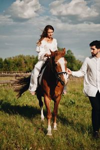 Man with woman riding horse on field