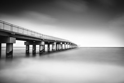 Bridge over calm sea against sky