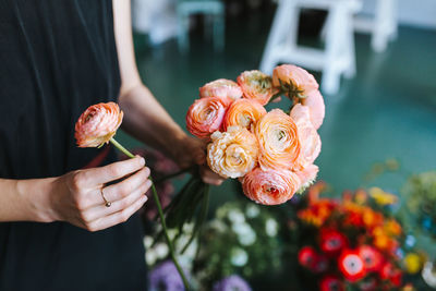 Midsection of florist arranging flowers while working in store