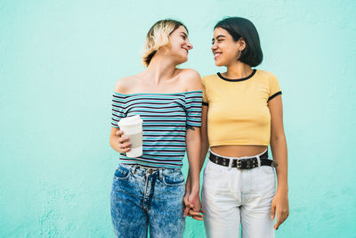 Happy friends standing against wall