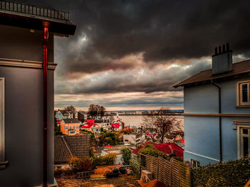 Buildings by sea against sky during sunset