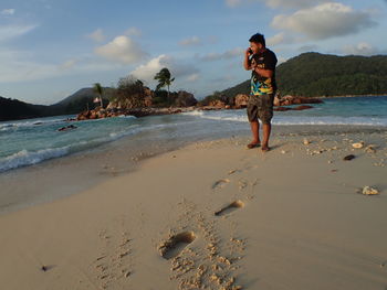 Full length of man standing on beach against sky