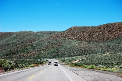 Road by mountain against clear blue sky