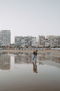 Full length of man on beach against buildings in city