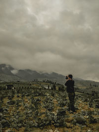 Rear view of man standing on mountain against sky