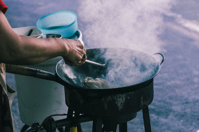 Cropped hand of person preparing street food in city