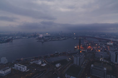 High angle view of illuminated cityscape by sea against sky