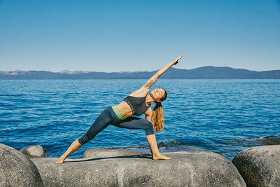 Young woman practicing yoga on lake tahoe in northern california.