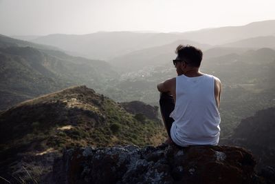 Young man looking at mountains against sky