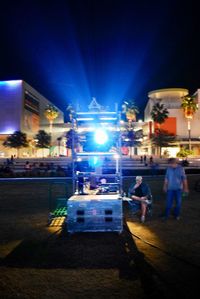 People at illuminated city against sky at night