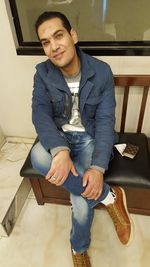 Portrait of young man sitting on chair at home