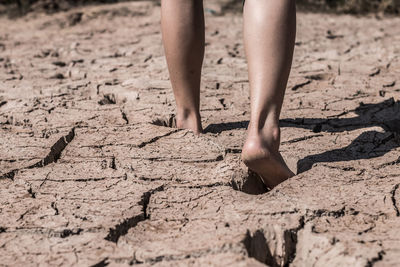 Low section of person walking on barren land