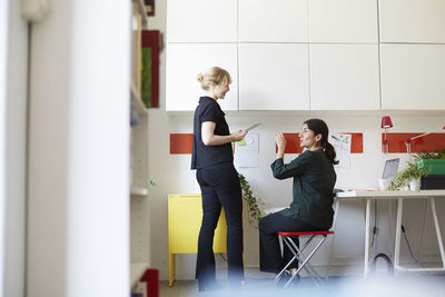 Full length of mid adult businesswoman talking with colleague in office