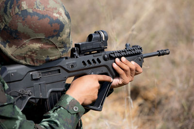 Close-up of army soldier aiming with rifle