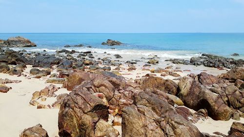 Rocks on beach against clear blue sky