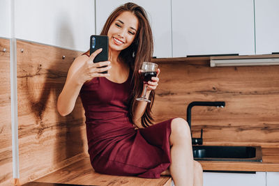 Young woman using mobile phone while sitting on floor at home