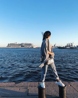 Woman standing by sea against clear sky