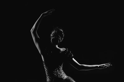 Midsection of man with arms outstretched against black background