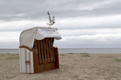 Hooded beach chair on shore against sky