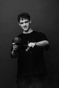 Portrait of young man standing against black background