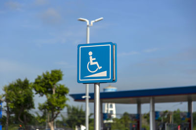 Low angle view of road sign against blue sky