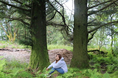 Woman sitting on tree trunk in forest