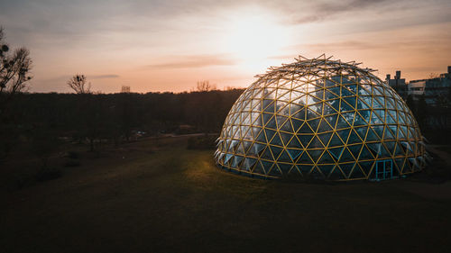 Metallic structure on field against sky during sunset