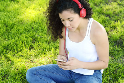 Woman listening music while using mobile phone on field