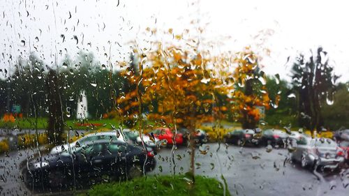 Cars in parking lot seen through wet window in rainy season