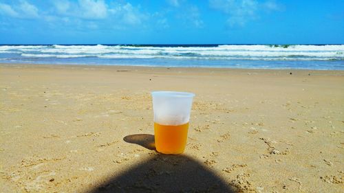 Beer in disposable glass on sand at beach