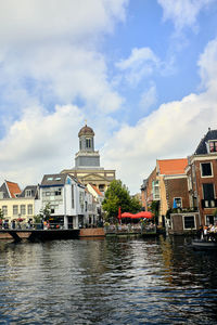 Canal amidst buildings in city against sky