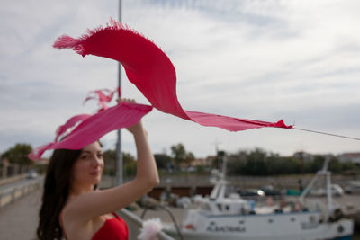 Portrait of woman standing by flags over pier at harbor