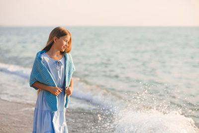 Stylish teenge kid girl 12-14 year old wear trendy dress and knit blue cardiga in sea coast outdoor